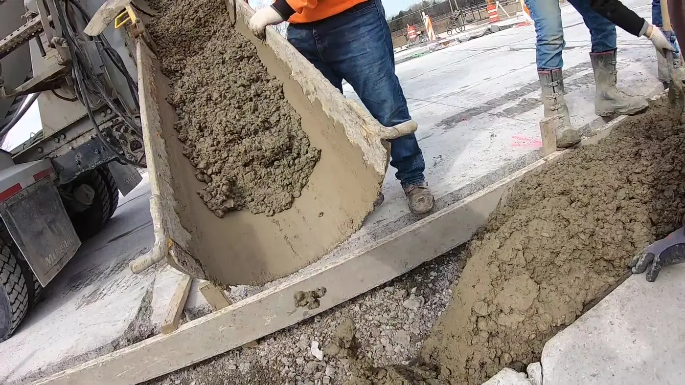 A crew pouring concrete from a truck chute into a form