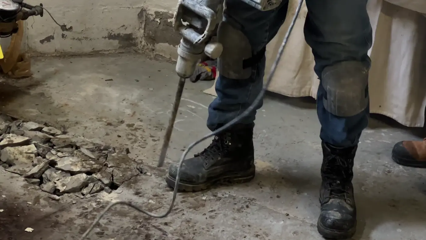 A worker breaking out a damaged concrete slab section